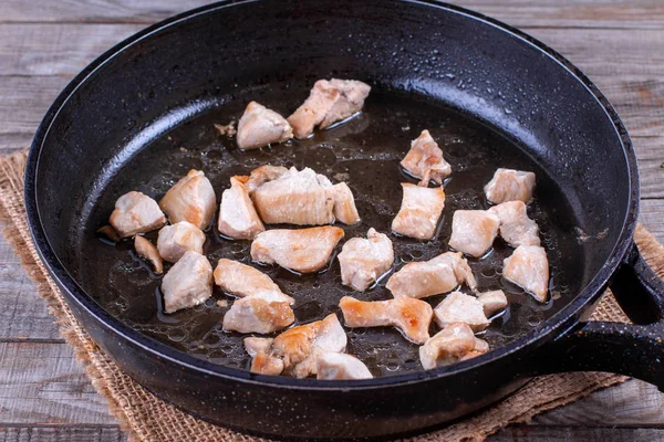 Chopped chicken fillet fried on frying pan with raw meat — Stock Photo, Image