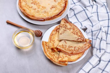 Beyaz tabakta ballı ince krepler.