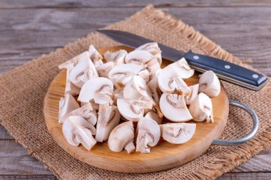 Ahşap tahta üzerinde taze dilimlenmiş champignon mantar