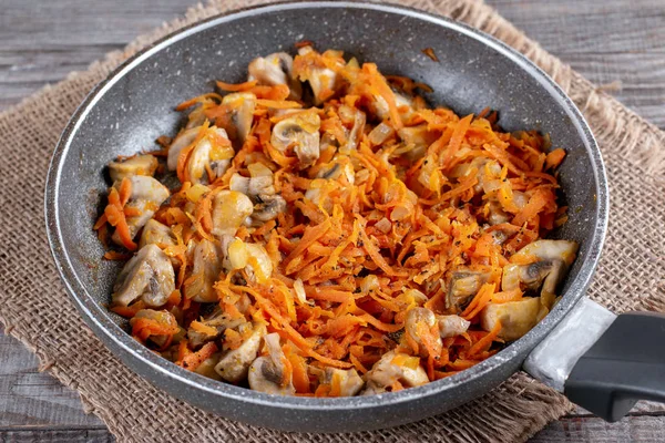 Cebola frita e cenoura com cogumelos na panela de ato de fritar — Fotografia de Stock