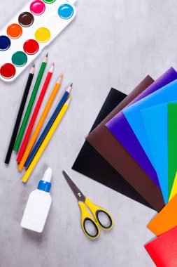 Uygulama için ayarlandı: kağıt, yapıştırıcı, makas, gri arkaplan üzerindeki boyalar