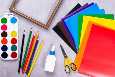 Uygulama için ayarlandı: kağıt, yapıştırıcı, makas, boyalar, gri arkaplan üzerindeki çerçeve