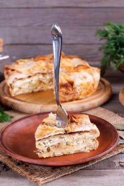 Tahta bir masada peynirli ve otlu ev yapımı turta.