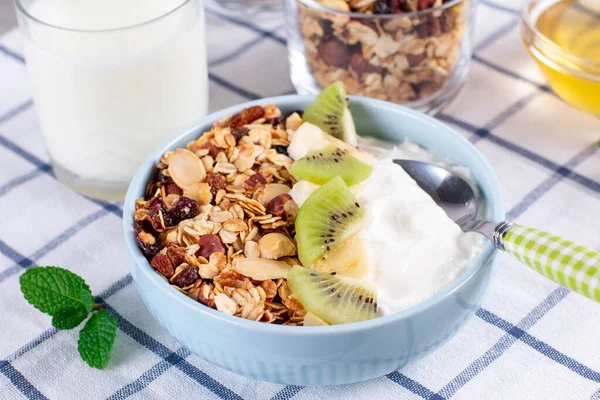 Granola with Greek yogurt kiwi and banana in a bowl with a spoon. Fitness diet for weight loss, proper and tasty food