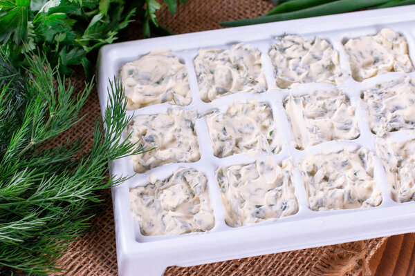 Frozen cubes of herbs with butter on a wooden table
