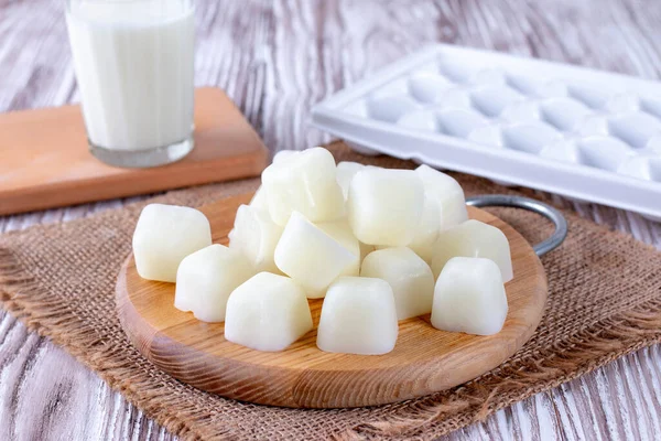 Milk ice cubes on a cutting board a white wooden table