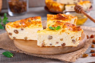 Tabakta kuru üzüm olan peynirli güveç, ahşap masa, yakın plan.