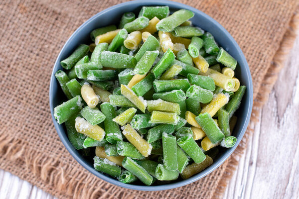 Замороженные зеленые бобы в миске на деревянном столе
