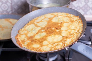 İnce krepler tavada kızartılır. Ev yapımı yemek.