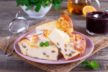 Masanın üzerinde kuru üzüm ve pudra şekerli süzme peynir güveci.