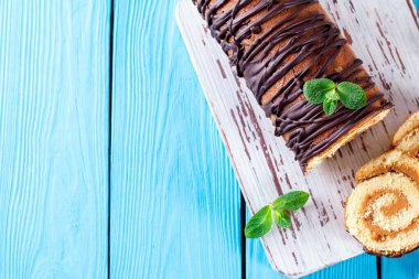 Mavi arka planda sünger kek rulosu. Boşluğu kopyala.