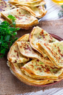 Ahşap bir masada maydanozlu kabak gibi ince krepler, yakın plan.