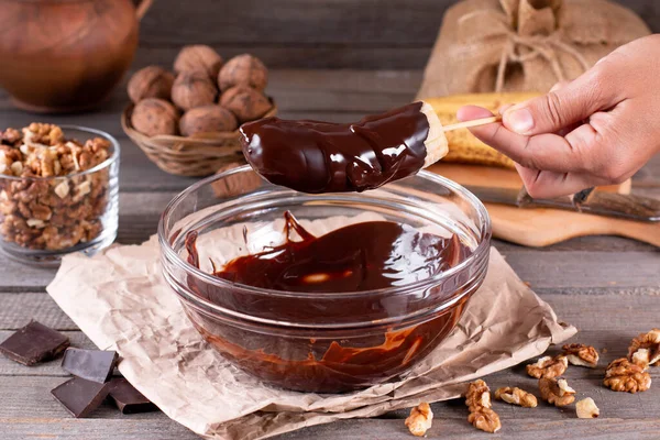 Woman hands pour frozen banana with chocolate. Frozen Chocolate Covered Bananas on a Stick