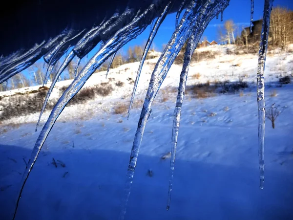 Angled icicles on a snowy roof edge — Stock Photo, Image