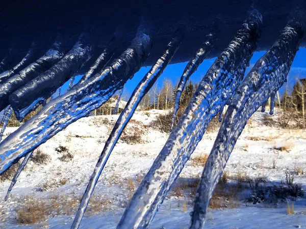 Hoekige ijspegels op een besneeuwde dakrand — Stockfoto