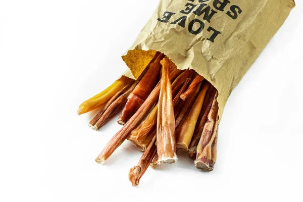 Beyaz arka planda bir kese kağıdının içinde bir yığın doğal köpek maması, kabadayı sopaları. Kağıt torba baskısı diyor ki, sev beni..