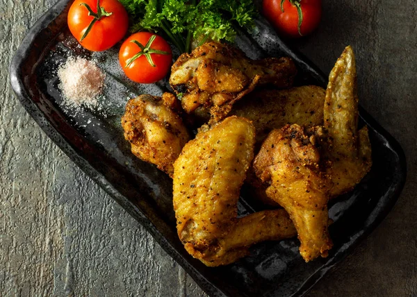 Ev yapımı, bedava ve organik hindistan cevizi yağı kızarmış tavuk kanadı. Domates ve maydanozla süslenmiş himalaya tuzu.. 