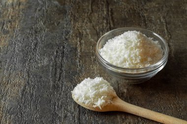 Cam kasede organik hindistan cevizi parçacıkları ve bir kaşık dolusu hindistan cevizi parçacıkları..