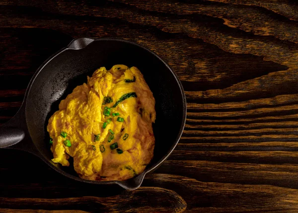 Kızarmış organik doğal tavuk yumurtaları, siyah bir tavada. Taze soğanla servis edilir..