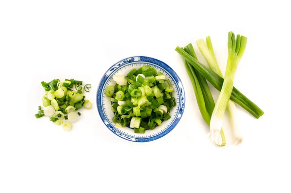 Doğranmış taze soğan, soğan, beyaz arka planda mavi bir tabakta.