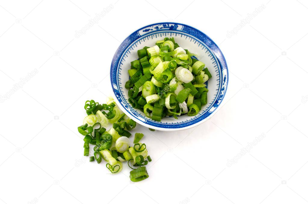 chopped spring onion, scallions, in a blue dish on white background