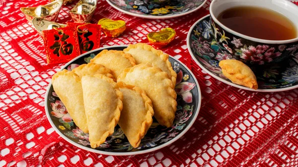 Süsler, kırmızı cepler ve madeni paralar üzerindeki Çin sembolleri zenginlik anlamına gelir. Bol yağda kızartılmış cepli çay seti, yau gok. Geleneksel Çin Yeni Yıl Atıştırması Kutlama sezonunda.