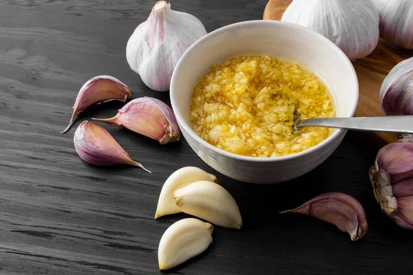 Sarımsak, soğan ve sarımsak kasede koyu ahşap arka planda.