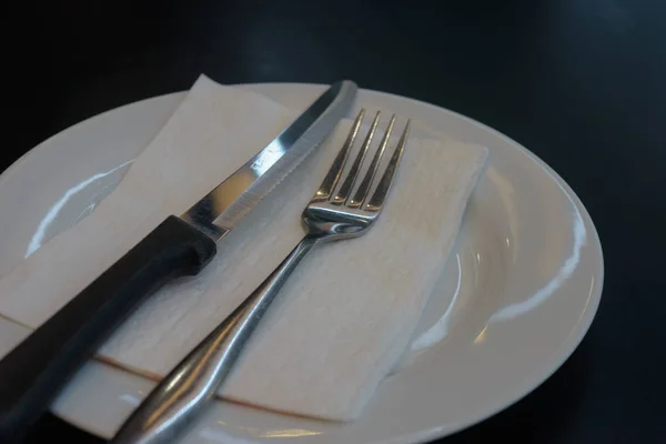 Tenedor y cuchillo plato blanco sobre mesa negra — Foto de Stock