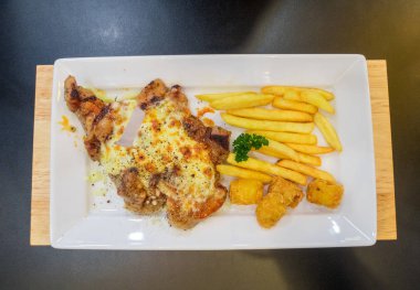 Domuz bifteği duble peynir ve patates kızartması beyaz bir tabakta servis edilir.