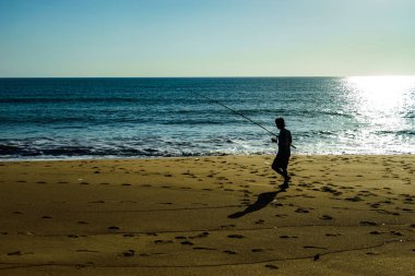 Sahilde yürüyen balıkçı.