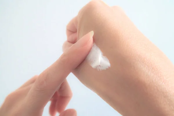 Close-Up Mujer aplicación de la mano crema hidratante sobre fondo blanco — Foto de Stock