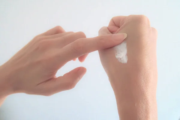 Close-Up Mujer aplicación de la mano crema hidratante sobre fondo blanco — Foto de Stock