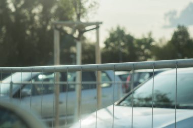 Arka planda arabalı bir park yeri etrafında çit