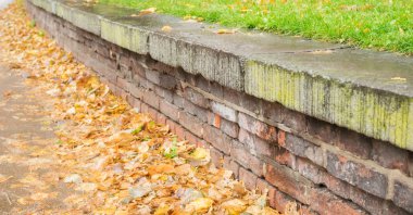 Birçok sonbahar yaprakları ile taş duvar