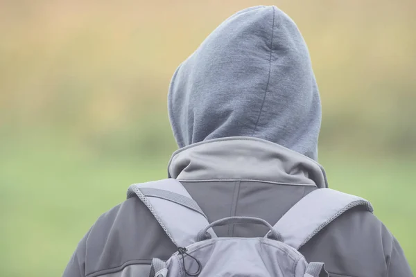 Man with hood and backpack from behind with soft bokeh — Stock Photo, Image