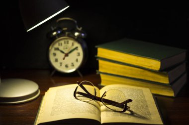 Masada kitap ve gözlük. Lambanın altında akşam okumaları..
