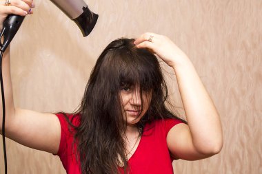 Genç bir esmer kız saçını kurutuyor..