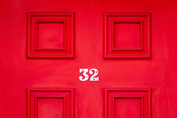 32 numaralı ev, parlak kırmızı ahşap ön kapıda.