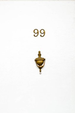 House number 99 on a white wooden front door in London, England clipart