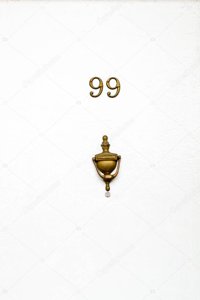 House number 99 on a white wooden front door in London, England