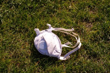 Dışardaki çimlerin üzerinde duran yüz maskesi.