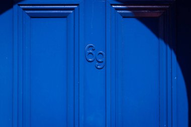 69 numaralı ev tek renkli kraliyet mavi ahşap ön kapıda.