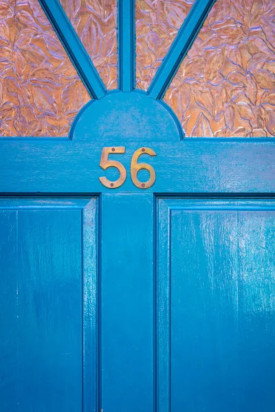 56 numaralı ev, parlak mavi ahşap ön kapıda.