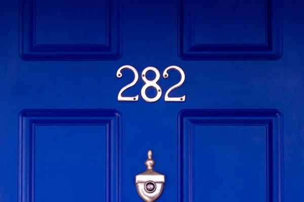 House number 282 on a dark blue wooden front door seen in detail