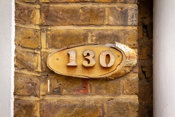 130 numaralı ev ahşap bir levhaya kazınmış tuğla bir duvarda.