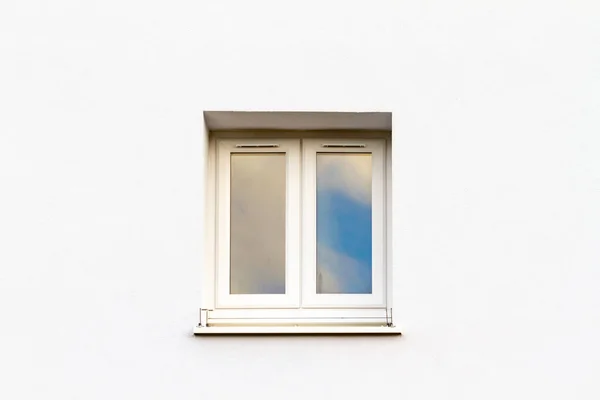 Simple white window in a white frame on a white house wall