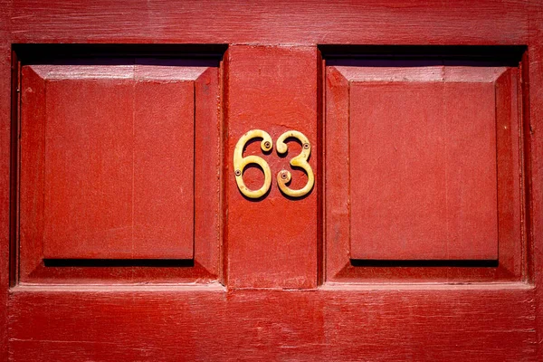 63 numaralı ev kahverengi ahşap ön kapıda.