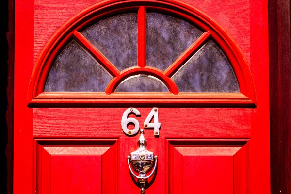 64 numaralı parlak kırmızı renkli ev. Pencere ve kapı tokmağı olarak yarım daire şeklinde cam.