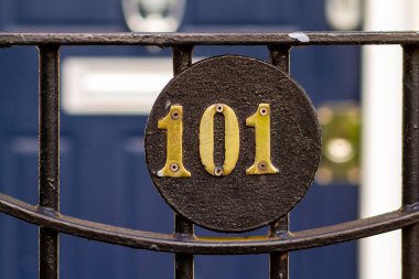 House number 101 on a round plaque in front of a blue wooden front door clipart