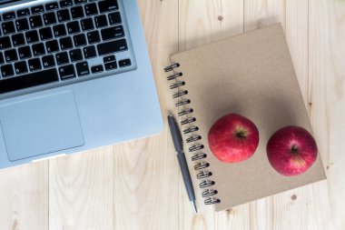 Kırmızı elma laptop, defter ve kalem ile ışık ahşap backgro